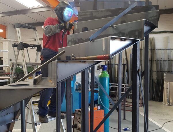 Fabricator welding a steel staircase frame in our Norwich workshop