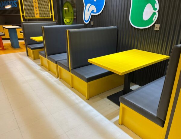 Fabricated restaurant booth seating with yellow tables and black upholstery, installed on site