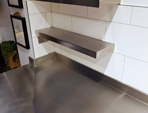 Stainless steel floating shelf mounted on a tiled wall