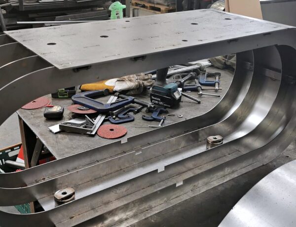 Stack of curved laser-cut steel sections awaiting assembly