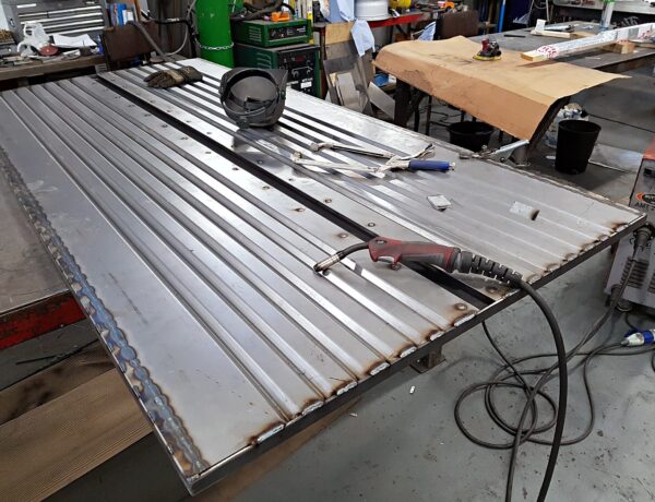 Long slatted steel door panel on the workshop bench