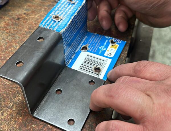 CNC punched steel bracket close-up in the SAMS Fabrications workshop